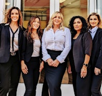 a group of women in business attire posing for a photo