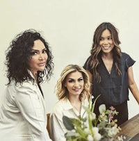 three women posing for a photo in front of a table